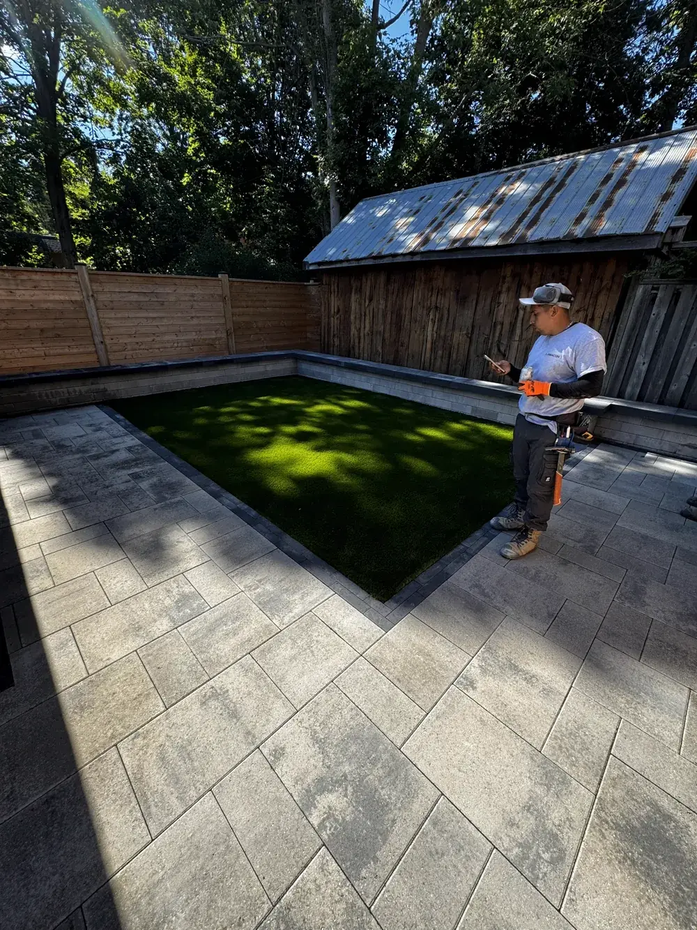 Trade crew member checking a phone on a finished patio
